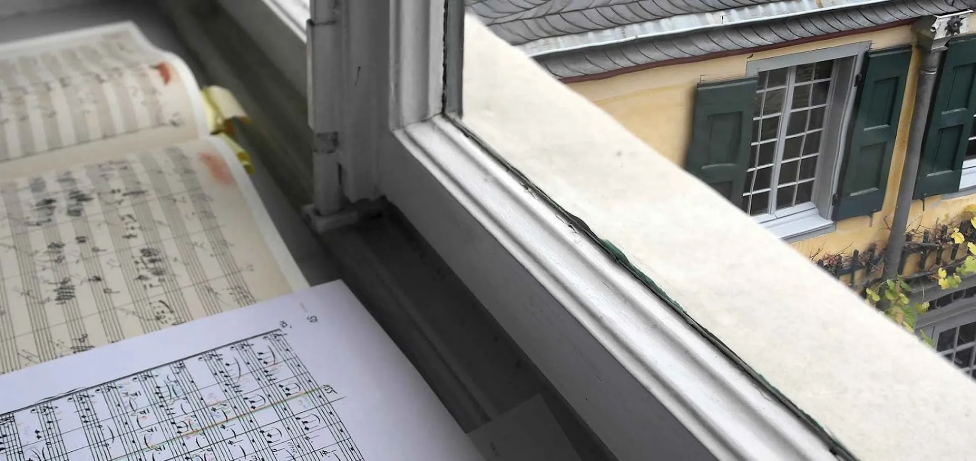 Sheet music lies on the windowsill of an office. Through the window you can see Beethoven's birthplace and home.